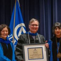 Provost and President post with man for picture on stage